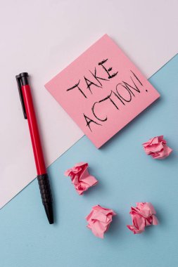 Take Action 'ı gösteren bir not yazıyorum. Ticari fotoğraf sergisi resmi bir şey yapmak ya da sorunlu bir hedefe ulaşmak için uyumlu bir şey yapmak. Not kağıtları ve sabitleyici yumuşak arkaplan üzerine yerleştirilmiş.