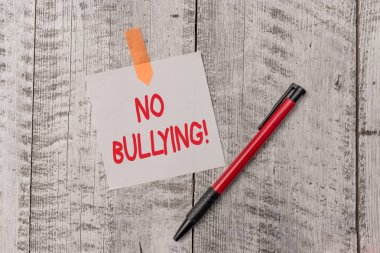 Zorbalık Yok'u gösteren metin işareti. Kavramsal fotoğraf çocuklar arasında agresif davranış durdurmak güç dengesizliği Bir düz boş kağıt levha ve ahşap dokulu masa ile bağlı bir kalem.