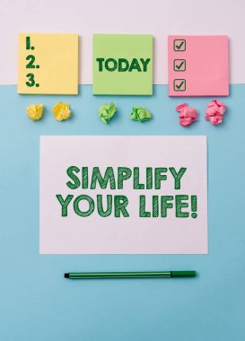 Hayatını Basitleştir 'i gösteren bir not yazıyorum. İş fotoğraflarının gösterimi önemli konulara odaklandı ve bırak da başkaları daha azı için endişelensin. Not kağıtları ve sabit kağıtlar yumuşak kirişlerin üzerine yerleştirildi.