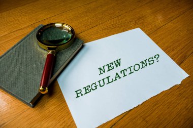 Yeni Düzenlemeler sorusunu gösteren metin işareti. Kavramsal fotoğraf kuralları bir şey yapılır şekilde kontrol etmek için hükümet sipariş yaptı Elektronik cihaz gadget büyüteç cam dinlendirme ahşap masa kadar yakın.