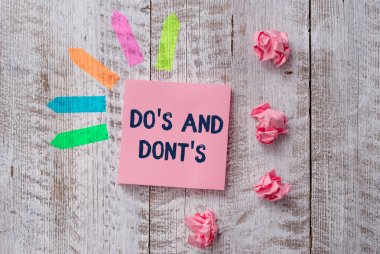 El yazısı metin yazma Do S Ve Dont S. Kavram anlamı Kurallar veya gümrük bazı faaliyet veya eylemler ile ilgili Düz not kağıt ve satır ok çıkartmaları ahşap masa nın üstüne.