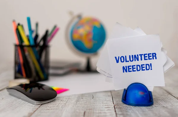 Handwriting text Volunteer Needed. Concept meaning need work for organization without being paid Stationary and computer stuffs with artificial globe on the wooden desk. — Stock Photo, Image