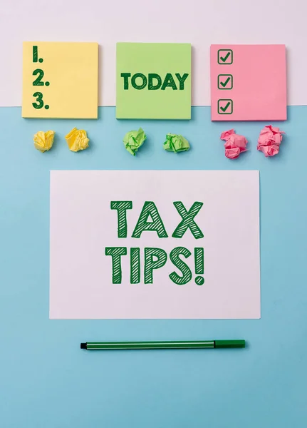 Writing note showing Tax Tips. Business photo showcasing compulsory contribution to state revenue levied by government Note papers and stationary placed sideways on top of softhued backdrop.