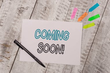 El yazısı metin Yakında. Kavram anlamı olay veya eylem gerçekten kısa bir süre sonra olacak Düz not kağıt ve çizgi ok çıkartmaları ahşap masa üzerinde kalem ile.