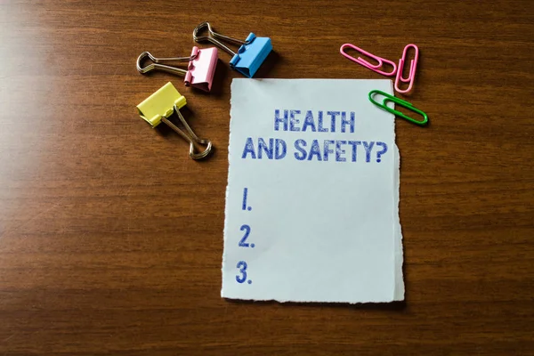 Handwriting text writing Health And Safety Question. Concept meaning regulations and procedures to prevent accident or injury Blank stationary paper set three colored clips binders lying wooden table. — Stock Photo, Image