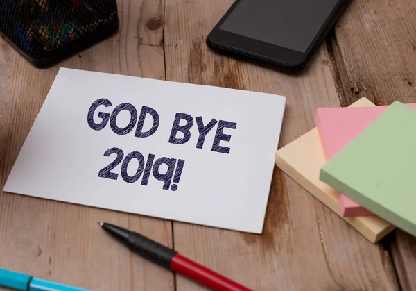 Word writing text God Bye 2019. Business concept for express good wishes when parting or at the end of last year Top view wooden table stationary paper tablet pen colored stick pad notes.