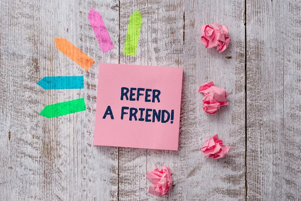 Handwriting text writing Refer A Friend. Concept meaning direct someone to another or send him something like gift Plain note paper and line arrow stickers on the top of wooden table desk. — стокове фото