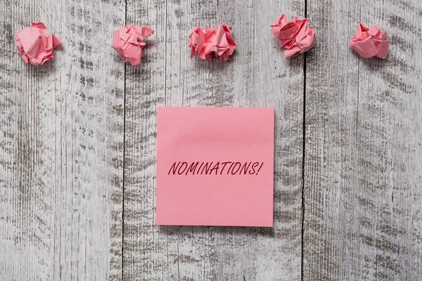 Woord schrijven tekst Nominaties. Business concept voor actie van nomineren of staat wordt genomineerd voor prijs Dikke set van gewone nota papier met restjes op de houten getextureerde tafel. — Stockfoto