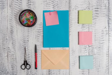 Ön görünüm kapalı renkli dikdörtgen zarf boş sayfa kağıt yapışkan not tükenmez makas klipleri tutucu retro vintage rustik eski kereste ahşap masa arka plan yalan