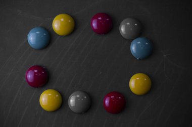 Tebeşir çizgi ile siyah tahta üstüne yerleştirilen aynı boyutlarda yuvarlak düz renkli taşlar. Kayalar klasik eski ahşap tahta sopa. Düz düzenleme sanatsal yolu fotoğraf bırakır