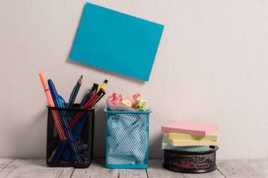 Mavi Yapışkan Kart Kalem, Kalem, Marker, Atık Kağıt ve Üstüne Renkli Stick Pad Notlar ile Mesh Ataç Pot dolu iki kalem tencere üzerinde asılı Beyaz Duvar abasın