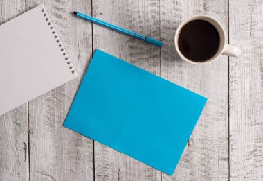 Ahşap arka planda kahve fincanının yanına ekipman yazmak. Masanın üstündeki bardağın yanına boş kağıt koyulmuş. Dairenin düzenlenmesinde sanatsal yol fotoğrafçılıktır