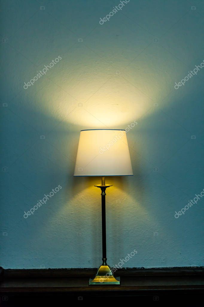 Metal base table lamp lighted lying wooden furniture colored background