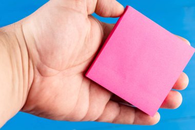 Kapalı görünüm renkli arka plan adam el yapışkan not tutan. Kare kağıt erkek palmiye tuttu. Fikirleri yazmak. Yapılacak şeyleri organize edin. Notları Hatırlat