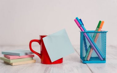 Ön görünüm kahve fincan ıstıraç sıcak içecekler boş renkli yapışkan not kalemleri metal tutucu yığılmış not pedleri retro vintage rustik eski masa arka plan yalan. Soyut tasarım. Boş not