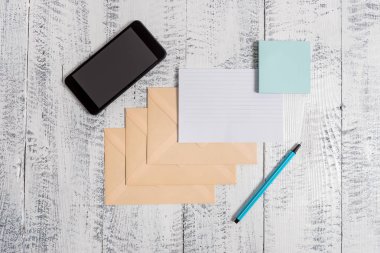 Üç kapalı dikdörtgen renkli zarf kağıt levha akıllı telefon yapışkan notlar pad marker ahşap retro vintage eski rustik arka plan yalan hüküm. Metni boş alır önemli olaylar