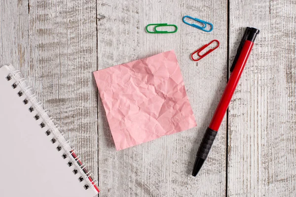 Zerknülltes Notizpapier und ein Notizbuch über dem Holztisch. Faltenblatt plus stationärer Stick auf klassischem Hintergrund in gekippter Position. künstlerische Art der flachen Lagen-Fotografie — Stockfoto