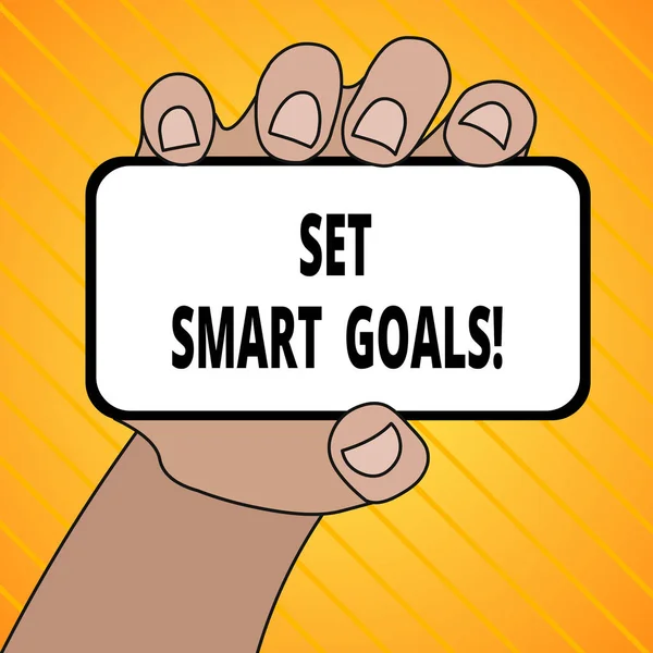 Text sign showing Set Smart Goals. Conceptual photo list to clarify your ideas focus efforts use time wisely Closeup of Smartphone Device Held in Hand with Blank Screen and Text Space.