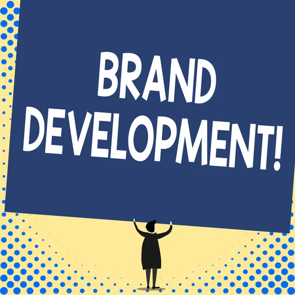 Word writing text Brand Development. Business concept for Defining the product to excel in the market Promoting Back view standing short hair woman dress hands up holding blank rectangle.