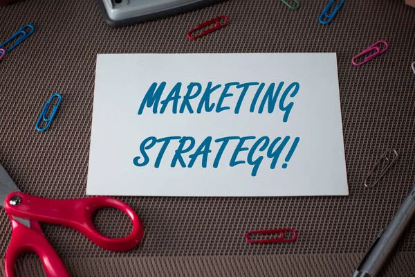 Text sign showing Marketing Strategy. Conceptual photo Scheme on How to Lay out Products Services Business Scissors and writing equipments plus plain sheet above textured backdrop.