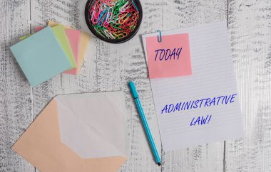 El yazısı metin yazma Idari hukuku. Kavram anlamı kural kuralları gövde bir hükümet tarafından oluşturulan siparişler zarf levha kağıt yapışkan not yastıkları kalem klipler tutucu ahşap arka plan.