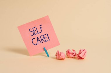 El yazısı metni Self Care. Eylem alma ya da kendi sağlığını geliştirmek kavramı anlamı uygulama düz Not kağıt ve sabit yumuşak pastel renk zemin üzerine yerleştirilen.