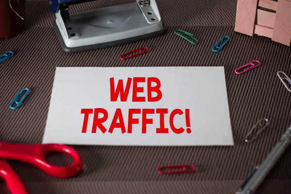 Text sign showing Web Traffic. Conceptual photo amount of data sent and received by visitors to website Scissors and writing equipments plus plain sheet above textured backdrop.