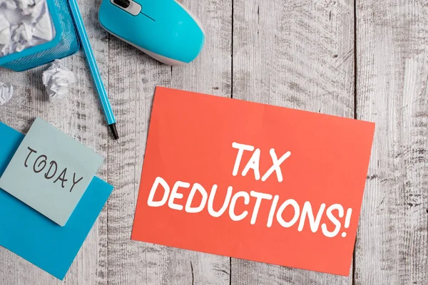 Handwriting text writing Tax Deductions. Concept meaning reduction income that is able to be taxed of expenses Crumpled paper in bin and computer mouse with stationary on wooden backdrop. — Stockfoto