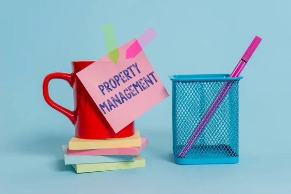 Handschrift tekst schrijven Property Management. Concept betekenis toezicht op onroerend goed bewaard gebleven waarde van Facility Cup Opmerking pijl banners gestapelde pads metalen pen houder pastel achtergrond. — Stockfoto