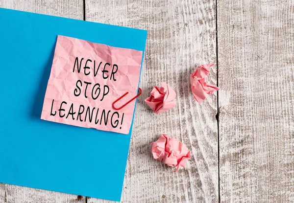 Writing Megjegyzés mutatja Never stop learning. Üzleti fotó bemutató tartani a tanuló egyre új ismereteket vagy anyagokat ránctalanító papír és karton fölé fa háttér. — Stock Fotó