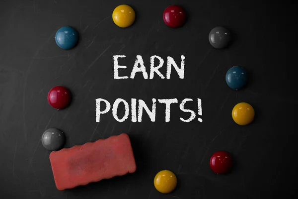 Word writing text Earn Points. Business concept for collecting big scores in order qualify to win big prize Round Flat shape stones with one eraser stick to old chalk black board.