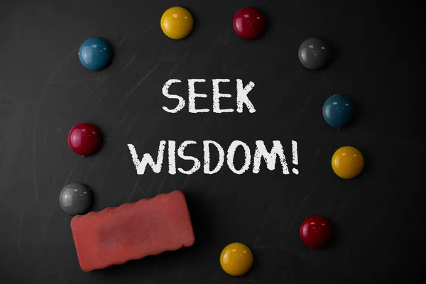 Word writing text Seek Wisdom. Business concept for ability to think act using knowledge experience understanding Round Flat shape stones with one eraser stick to old chalk black board.
