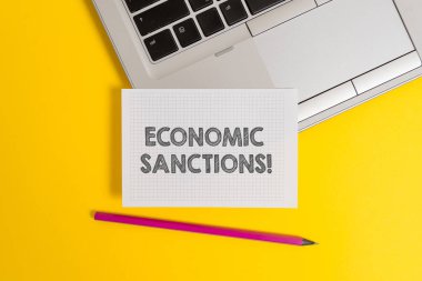 El yazısı metin yazma ekonomik yaptırımlar. Kavram anlamı ceza ceza başka bir ülkede ticaret savaş top trendy metalik dizüstü kalem kare kağıt levha renkli arka plan.