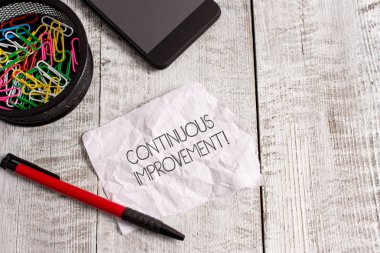 Word yazma metin sürekli Iyileştirme. Ilerleme için devam eden çaba için iş kavramı asla biten değişiklikler kırışıklık kağıt ve Notebook artı sabit ahşap arka planda yerleştirilmiş.