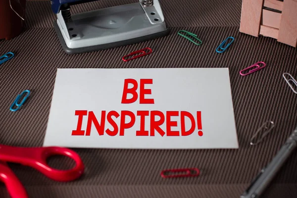 Text sign showing Be Inspired. Conceptual photo fill someone with urge or ability to do or feel something Scissors and writing equipments plus plain sheet above textured backdrop.