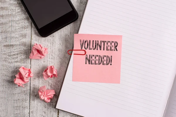 Conceptual hand writing showing Volunteer Needed. Business photo showcasing asking demonstrating to work for organization without being paid Notebook stationary placed above classic wooden backdrop. — Stock Photo, Image