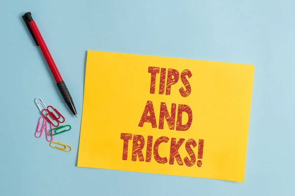 Handwriting text Tips And Tricks. Concept meaning means piece advice maybe suggestion how improve Plain cardboard and writing equipment placed above pastel colour backdrop. — Stock Photo, Image