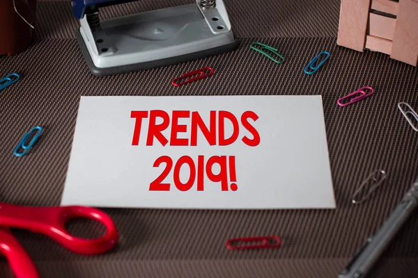 Text sign showing Trends 2019. Conceptual photo general direction in which something is developing or changing Scissors and writing equipments plus plain sheet above textured backdrop.