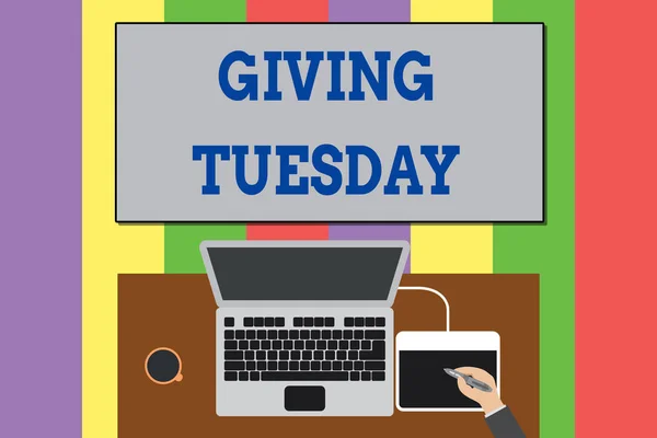 Text sign showing Giving Tuesday. Conceptual photo international day of charitable giving Hashtag activism Upper view laptop wooden desk worker drawing tablet coffee cup office.