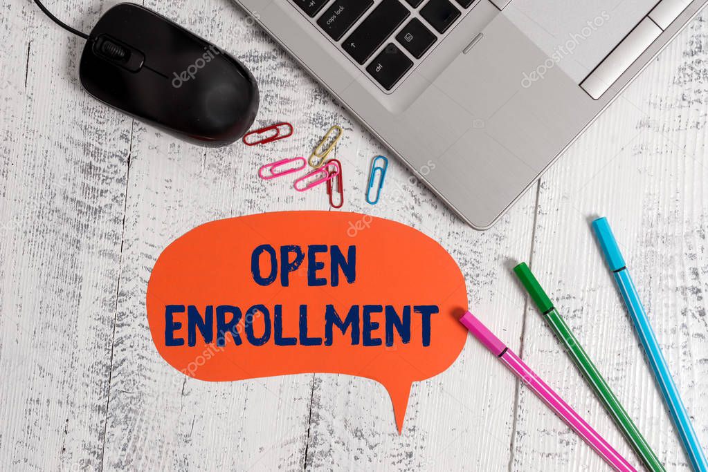 Text sign showing Open Enrollment. Conceptual photo The yearly period when showing can enroll an insurance Metallic slim laptop speech bubble colored clips pens mouse wooden vintage.