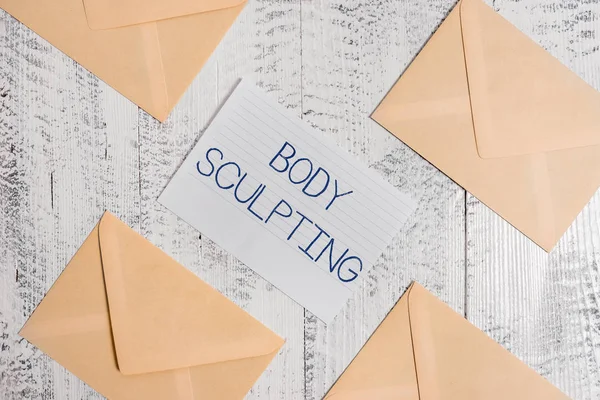 Text sign showing Body Sculpting. Conceptual photo activity of increasing the body s is visible muscle tone Four envelopes around ruled paper sheet old wooden vintage background.