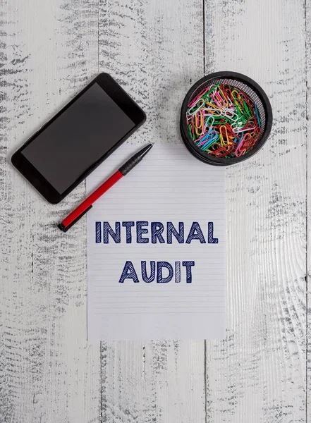 Conceptual hand writing showing Internal Audit. Business photo text Evaluates the effectiveness of the controls and processes Smartphone paper sheet clips ballpoint wooden vintage background.