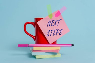 Kelime yazma metni Sonraki Adımlar. Başka bir şey bitirdikten sonra yapmak ya da plan bir şey için İş konsepti Cup yapışkan not ok afiş yastıkları yastıkları kalem pastel arka plan yalan yığılmış.