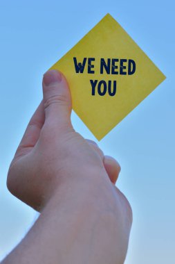 El yazısı metin yazma We Need You. Atama görevi veya yükümlülüğünün ihtiyaçlarını karşılamak için kavram anlamı Bir el yükselterek bir eliyle nota tutma vermek için kare kağıt kullanımı Parçası.