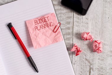 Writing note showing Budget Planning. Business photo showcasing The written description about current and future expenses Wrinkle paper notebook and stationary placed on wooden background. clipart