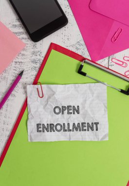 Conceptual hand writing showing Open Enrollment. Business photo showcasing The yearly period when showing can enroll an insurance Clipboard sheet pencil smartphone clips notepad wooden back. clipart
