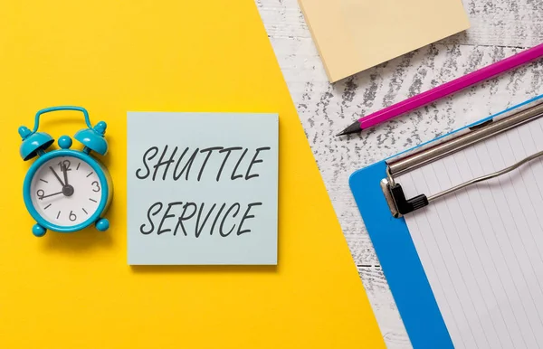 Word írás szöveg shuttle szolgáltatás. Üzleti koncepció járművek, mint a buszok gyakran két hely között notepads vágólap színes papír lap marker ébresztőóra fa háttér. — Stock Fotó