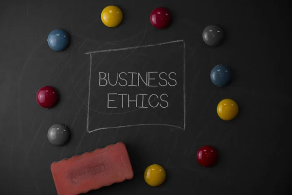 Text sign showing Business Ethics. Conceptual photo Moral principles that guide the way a business behaves Round Flat shape stones with one eraser stick to old chalk black board. — Stock Photo, Image