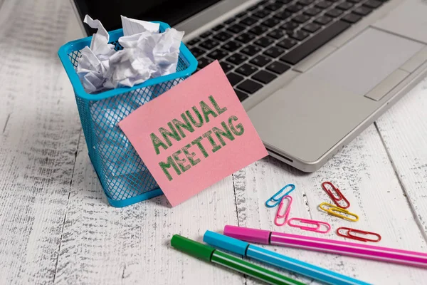 Writing note showing Annual Meeting. Business photo showcasing yearly meeting of the general membership of an organization Laptop sticky note waste basket crushed paper clips pens vintage table.