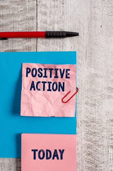 Word writing text positive action. Geschäftskonzept für gute Einstellung gegen bestimmte Situation feines Reaktionsfaltenpapier und Karton plus Schreibwaren über Holzgrund platziert. — Stockfoto